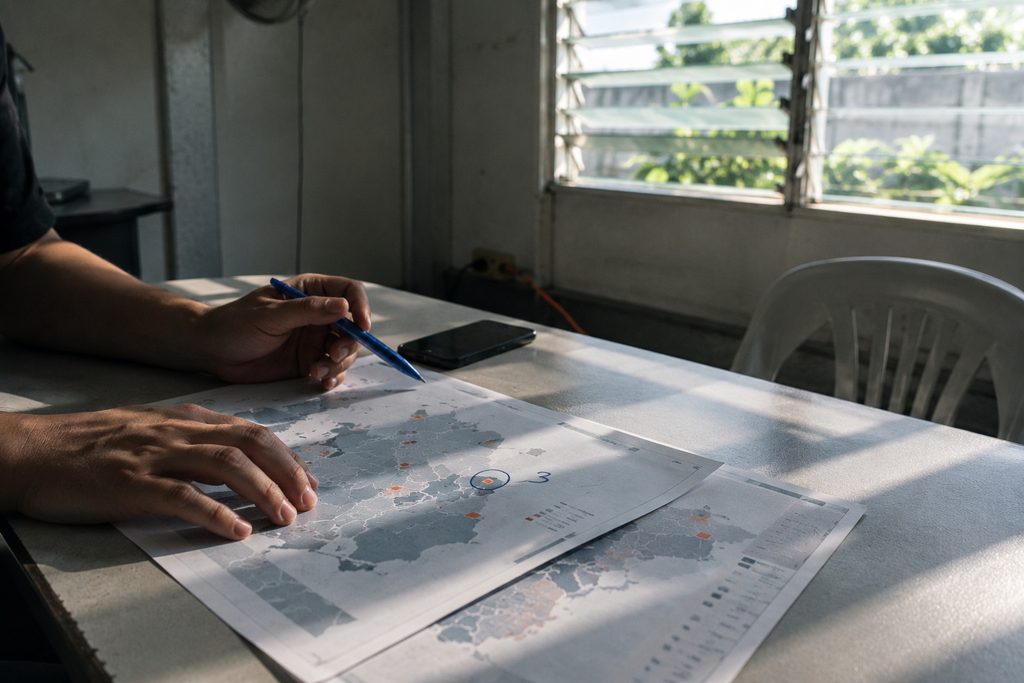 A printed market map on a plain table, one corner lifted, a pencil lying across it.